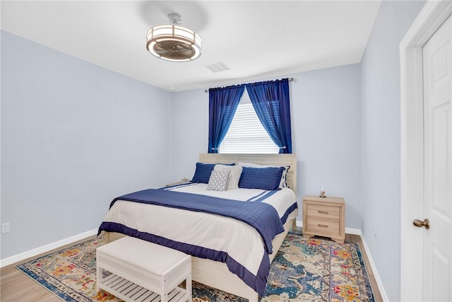 bedroom featuring baseboards, visible vents, and wood finished floors