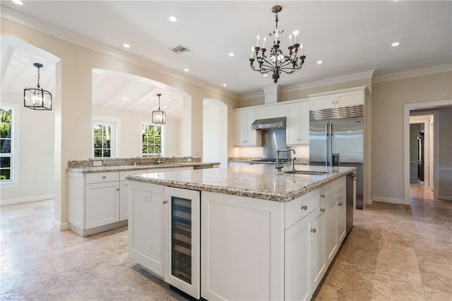 kitchen with a center island with sink, white cabinetry, and beverage cooler