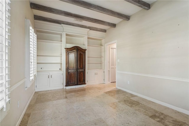 empty room with beamed ceiling and built in shelves