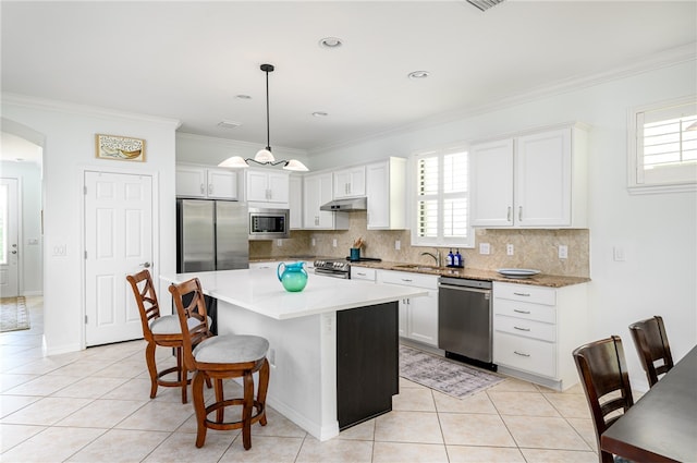 kitchen with pendant lighting, stainless steel appliances, white cabinets, and a center island