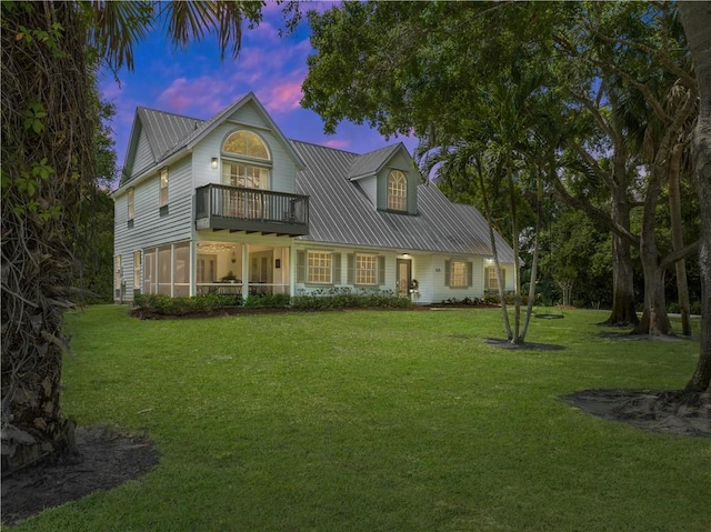 view of front of house with a balcony, a yard, and a sunroom