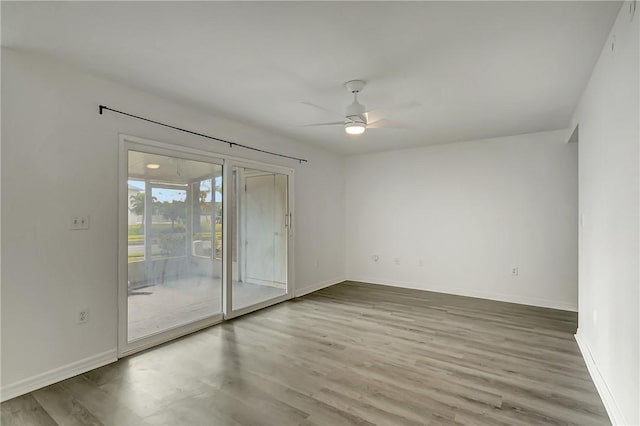 empty room featuring wood finished floors, a ceiling fan, and baseboards