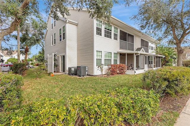 back of house with central AC unit, a lawn, and a sunroom