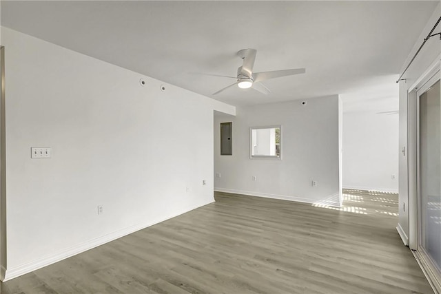 empty room with baseboards, electric panel, a ceiling fan, and wood finished floors