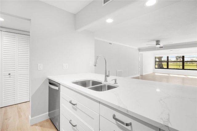 kitchen with sink, stainless steel dishwasher, light stone countertops, light hardwood / wood-style floors, and white cabinets