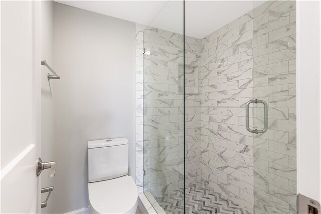 bathroom featuring a shower with shower door and toilet