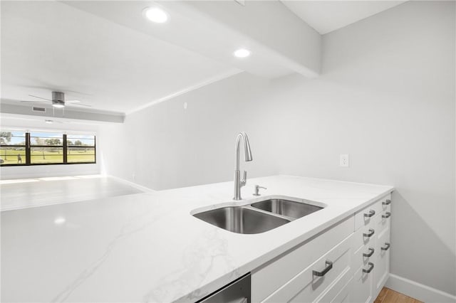 kitchen with sink, white cabinets, ceiling fan, light stone counters, and light hardwood / wood-style floors