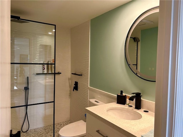 bathroom with toilet, vanity, and tiled shower