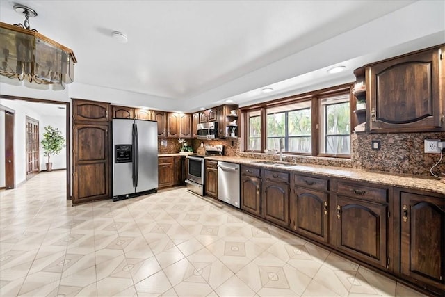 kitchen with appliances with stainless steel finishes, open shelves, a sink, tasteful backsplash, and dark brown cabinetry