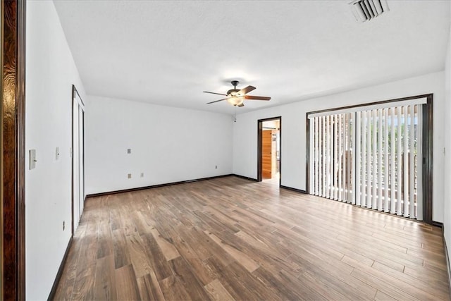 empty room featuring a ceiling fan, wood finished floors, and baseboards