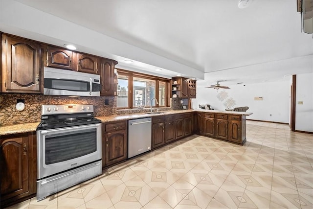 kitchen with appliances with stainless steel finishes, a sink, backsplash, dark brown cabinets, and recessed lighting