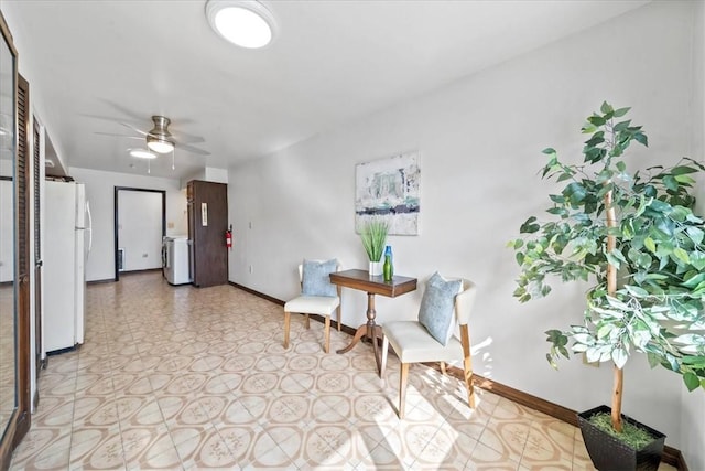 living area featuring baseboards, ceiling fan, washer / clothes dryer, and light flooring