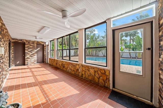 unfurnished sunroom featuring tile patterned flooring and ceiling fan