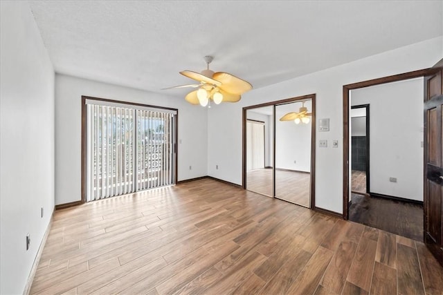unfurnished bedroom featuring wood finished floors, baseboards, and a ceiling fan