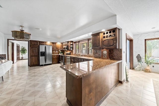 kitchen featuring stainless steel appliances, open shelves, healthy amount of natural light, and a peninsula