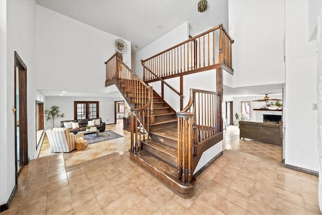 stairs with a high ceiling, a fireplace, tile patterned floors, and baseboards