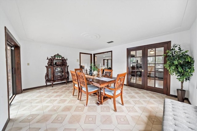 dining area featuring french doors, a wood stove, baseboards, and light tile patterned floors