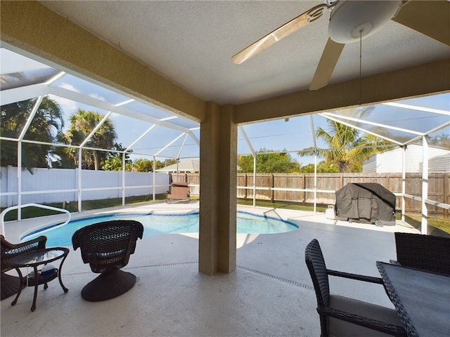 view of swimming pool with glass enclosure, grilling area, ceiling fan, and a patio