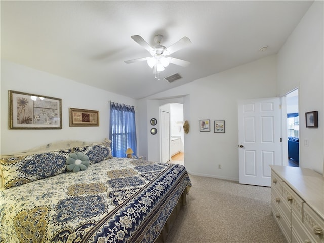 bedroom with ceiling fan, light carpet, vaulted ceiling, and ensuite bathroom