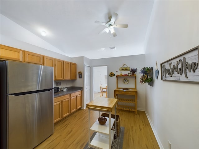 kitchen with ceiling fan, vaulted ceiling, light wood-type flooring, and stainless steel refrigerator