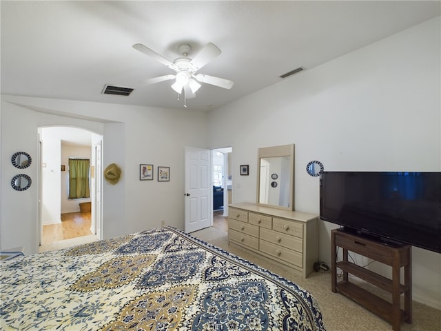 bedroom featuring ceiling fan, light colored carpet, lofted ceiling, and ensuite bath