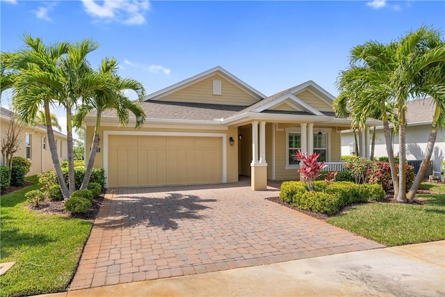 ranch-style house with decorative driveway, an attached garage, covered porch, and a shingled roof