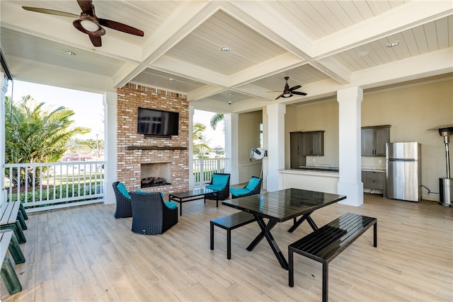 exterior space featuring ornate columns, light wood-type flooring, beam ceiling, and an outdoor brick fireplace