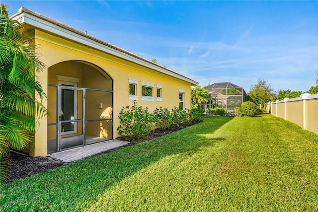 view of yard featuring glass enclosure and fence