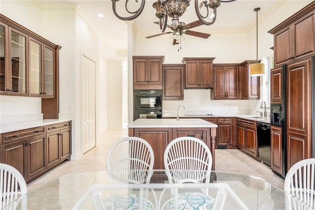 kitchen with an island with sink, hanging light fixtures, black appliances, a towering ceiling, and crown molding