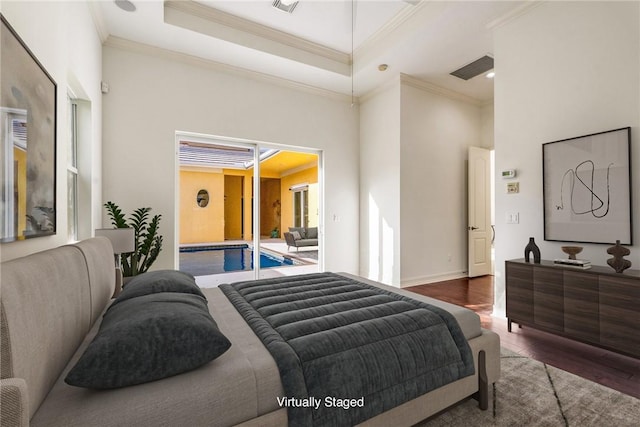 bedroom featuring baseboards, crown molding, a high ceiling, and wood finished floors