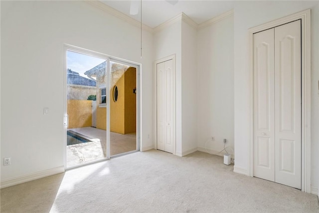 unfurnished bedroom with two closets, baseboards, carpet, and ornamental molding