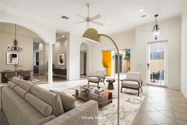 living room featuring baseboards, ceiling fan with notable chandelier, visible vents, and ornamental molding