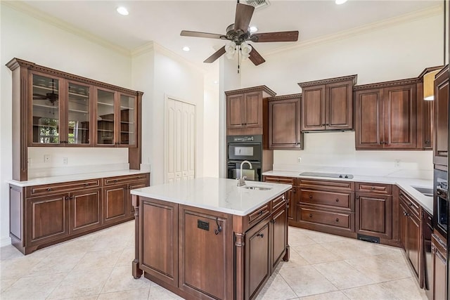 kitchen featuring black appliances, an island with sink, ornamental molding, a sink, and light countertops