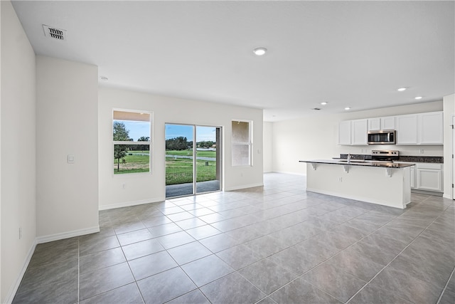 kitchen with white cabinetry, sink, stainless steel appliances, a breakfast bar area, and a kitchen island with sink