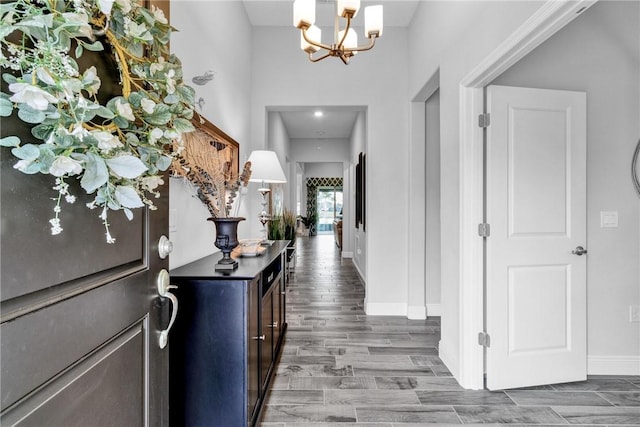 interior space with a notable chandelier, wood finished floors, and baseboards