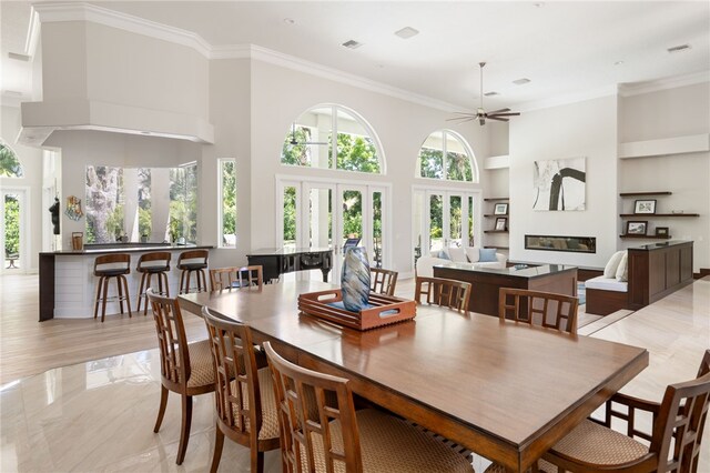 540 Marbrisa Dr, Vero Beach, FL 32963 - dining area featuring visible vents, a glass covered fireplace, built in features, a ceiling fan, and crown molding