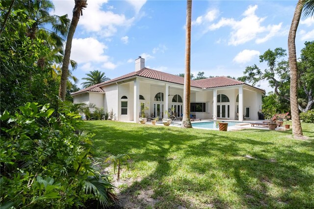 540 Marbrisa Dr, Vero Beach, FL 32963 - back of property featuring a chimney, an outdoor pool, a tiled roof, and a lawn