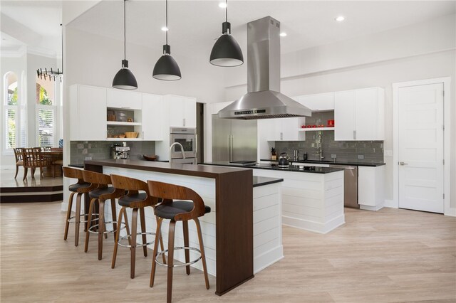540 Marbrisa Dr, Vero Beach, FL 32963 - kitchen featuring dark countertops, island range hood, decorative backsplash, open shelves, and an island with sink