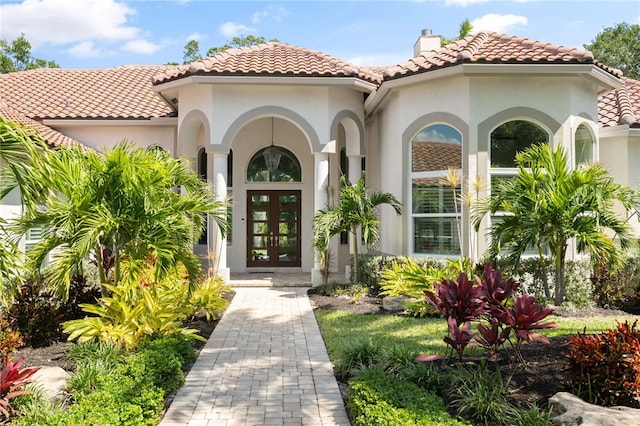 540 Marbrisa Dr, Vero Beach, FL 32963 - property entrance featuring french doors, a chimney, a tiled roof, and stucco siding