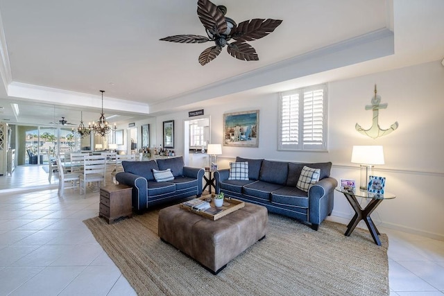 living area with a raised ceiling, ceiling fan with notable chandelier, and a healthy amount of sunlight