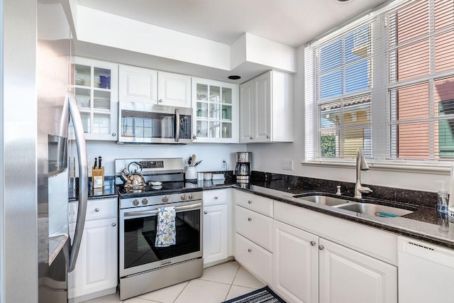 kitchen featuring glass insert cabinets, stainless steel appliances, light tile patterned flooring, white cabinetry, and a sink