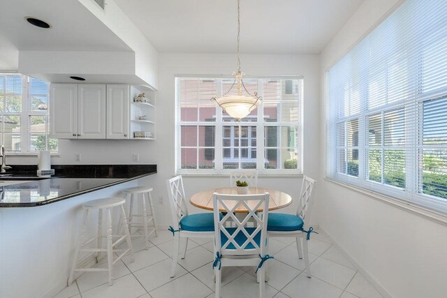 dining area featuring plenty of natural light, light tile patterned flooring, and baseboards