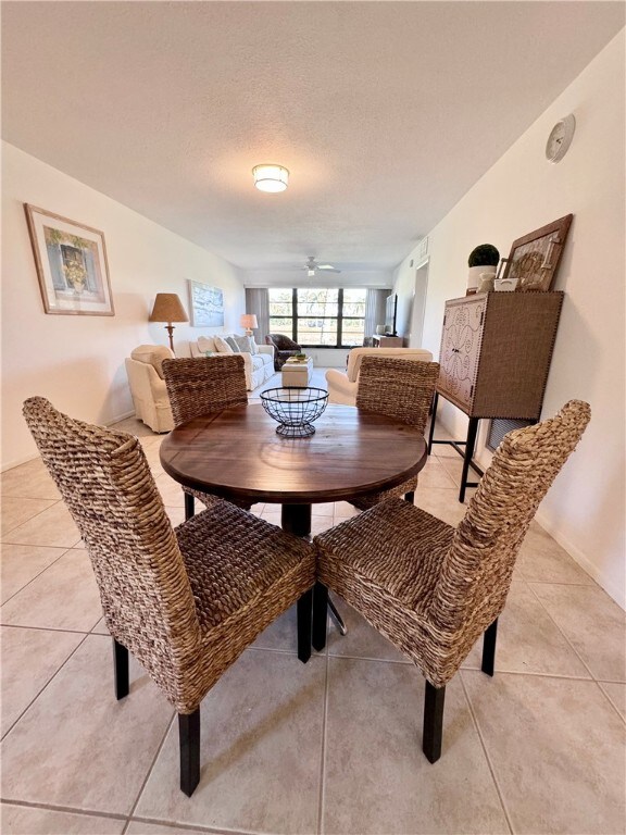 dining room featuring light tile patterned floors, a ceiling fan, and a textured ceiling