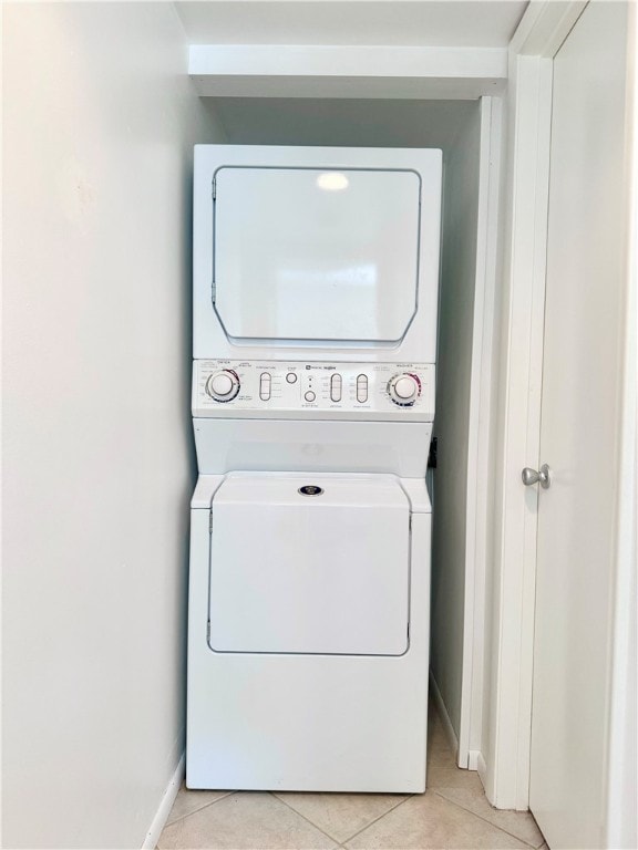 clothes washing area featuring stacked washer / drying machine and light tile patterned floors