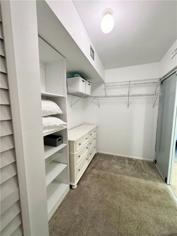 spacious closet featuring visible vents and dark colored carpet