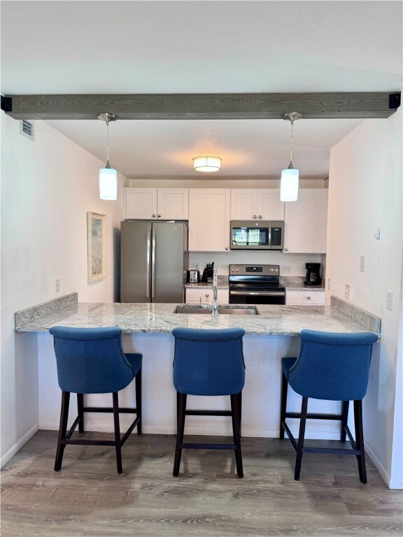 kitchen featuring a peninsula, appliances with stainless steel finishes, and white cabinetry