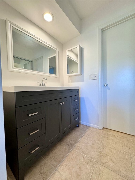 bathroom with tile patterned flooring, vanity, and baseboards