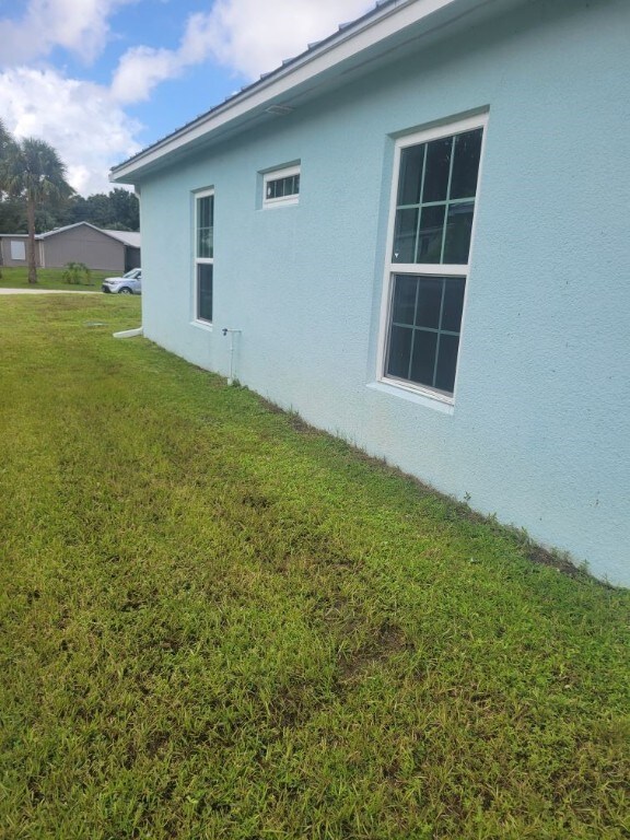 view of side of property with a yard and stucco siding