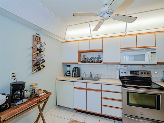 kitchen featuring tasteful backsplash, white cabinetry, light tile patterned floors, sink, and white appliances