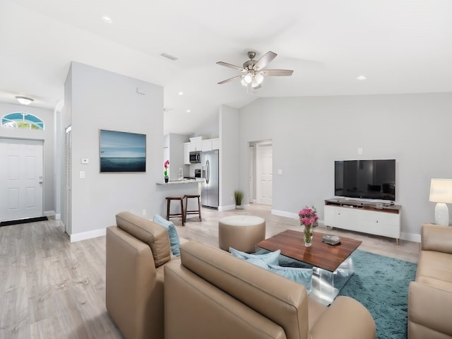 living room featuring light hardwood / wood-style flooring, ceiling fan, sink, and vaulted ceiling